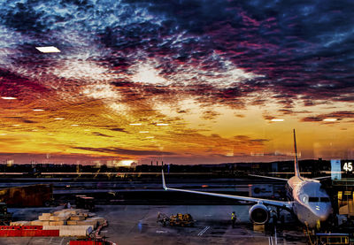 Airplane on runway against sky during sunset