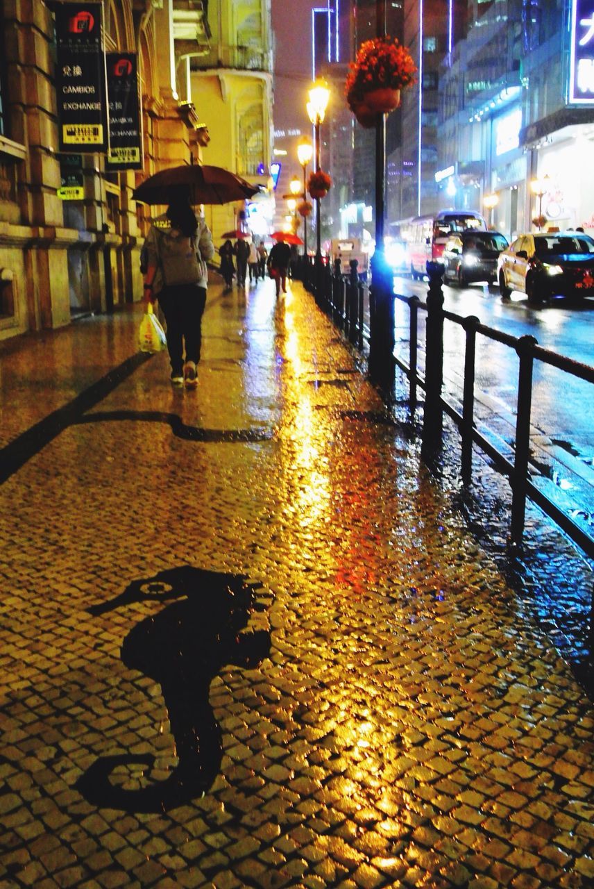 MAN WALKING ON WET STREET IN CITY