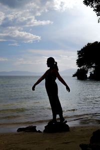 Full length of woman standing on beach against sky