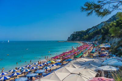 Group of people on beach against blue sky