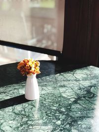 Close-up of flower vase on table by window