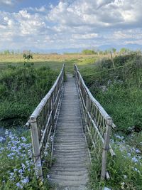 Boardwalk on field against sky