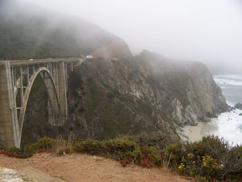 Arch bridge over mountains against sky