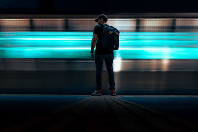 Rear view of man walking on illuminated city