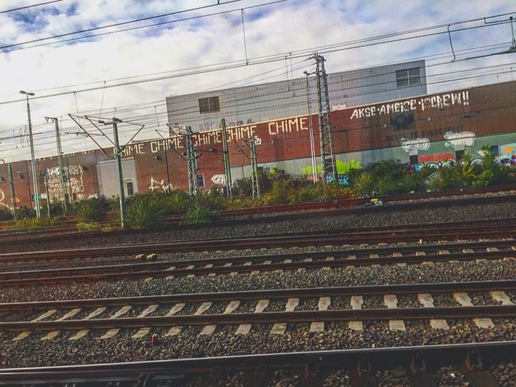 railroad track, rail transportation, public transportation, transportation, railroad station, railroad station platform, power line, sky, built structure, architecture, train - vehicle, building exterior, cable, electricity pylon, railway track, connection, train, passenger train, power supply, cloud - sky