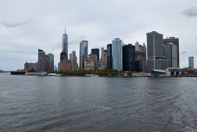 Modern buildings by river against sky in city