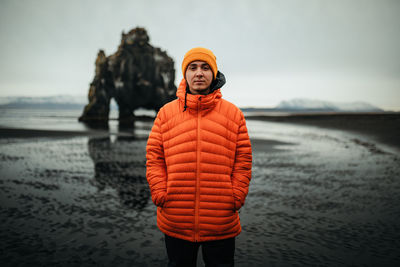 Young tourist near land in water and big stone cliff on blurred background