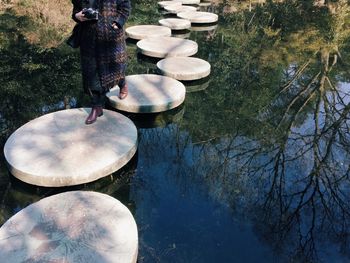 Low section of woman walking on stones over lake at hangzhou zoo