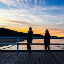 People standing on pier at sunset