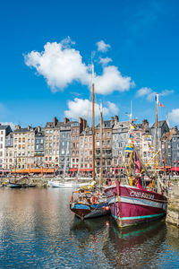 Boats moored at harbor against buildings in city