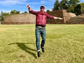 Portrait of man wearing sunglasses levitating over grassy field