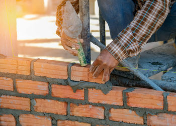 Low section of person holding umbrella against brick wall