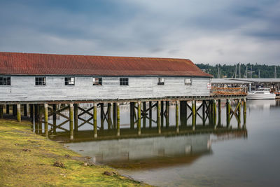 Pier over river by buildings against sky