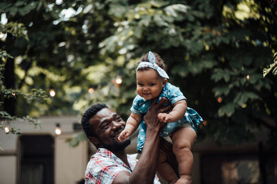 Father carrying daughter on shoulder outdoors