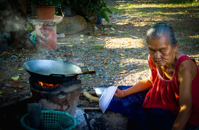 Midsection of woman with fire on barbecue grill