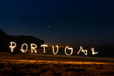 Illuminated light painting forming portugal text at beach