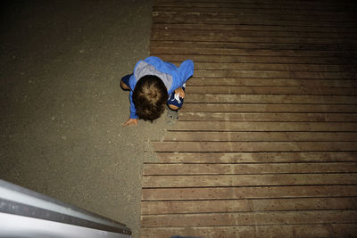 The kid's looking for bugs in the sand.