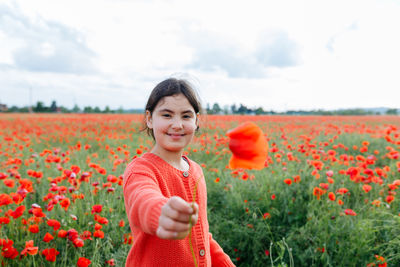 Portrait of young woman standing amidst yellow flowering plants on field against sky