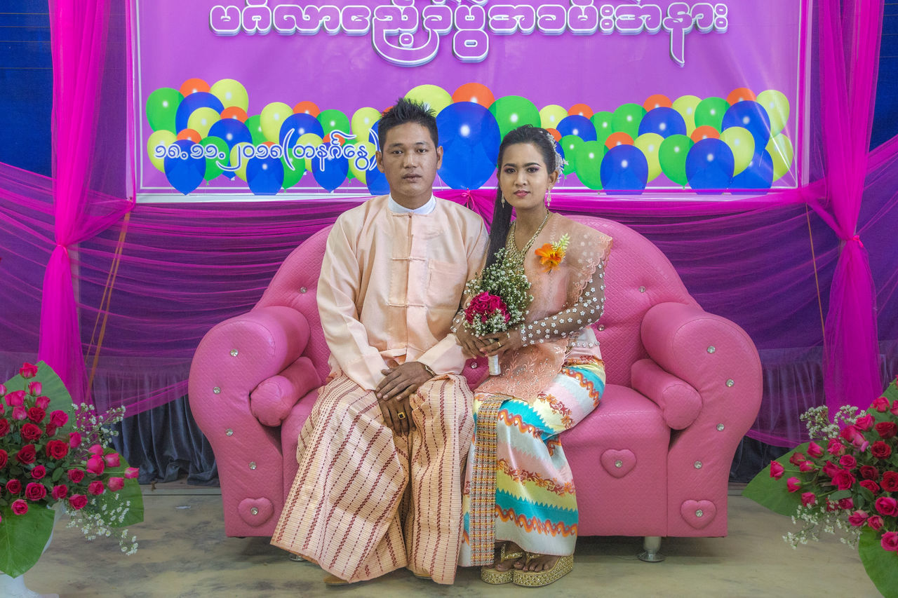 PORTRAIT OF A COUPLE HOLDING PINK WHILE SITTING