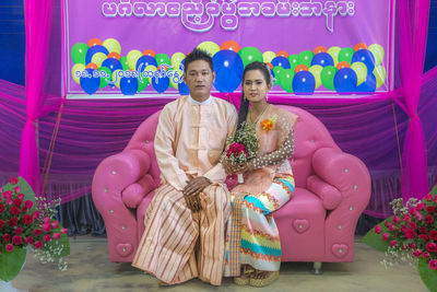 Portrait of a couple holding pink while sitting outdoors