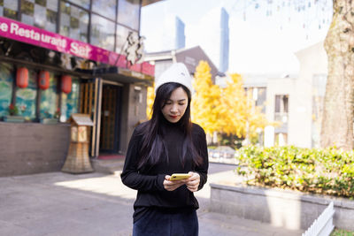 Portrait of young woman standing in city