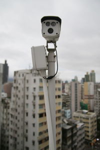 Low angle view of telephone pole against buildings in city