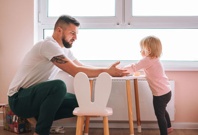 Young man father and baby girl little daughter playing in children room at home