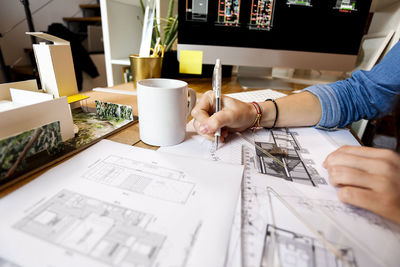 Young woman working in architecture office, drawing blueprints