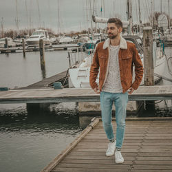 Portrait of a young man standing on pier on a cloudy day, weating casual clothes. 