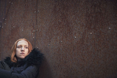 Young woman sitting against wall