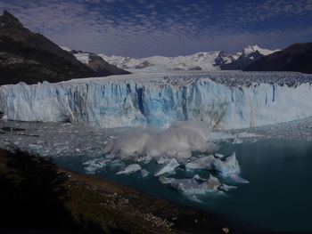 Scenic view of icebergs and snowcapped mountains against sky