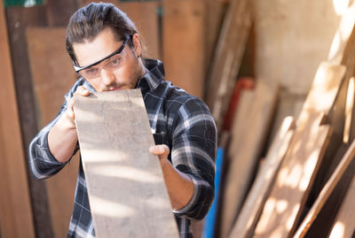 Young man looking away while standing on wood