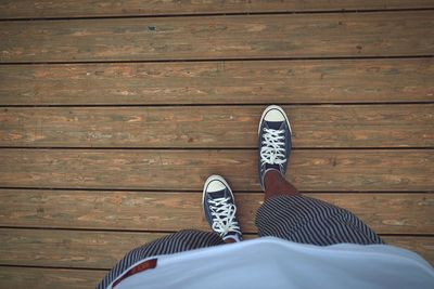 Low section of man standing on wooden floor