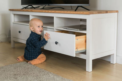 Side view of boy sitting on hardwood floor at home