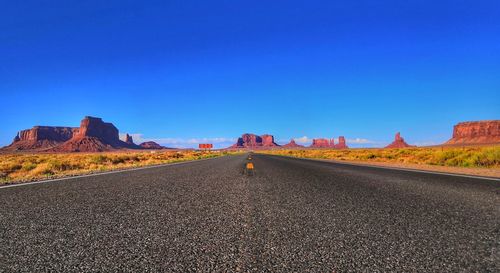 Surface level of road against clear blue sky an rocky formations