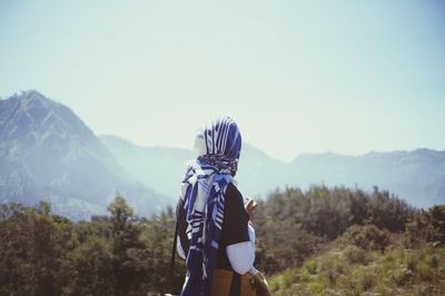 Rear view of woman standing on mountain against sky