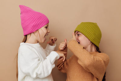 Smiling sister wearing knit hat against beige background