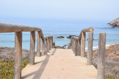 Wooden posts on beach against clear sky
