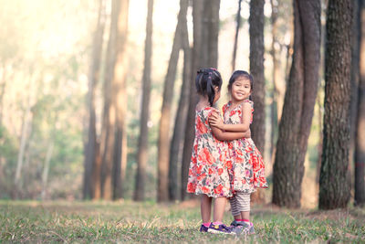 Happy girl standing by tree in forest