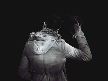 Rear view of woman standing against black background