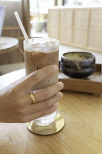 Cropped hand of woman using mobile phone on table