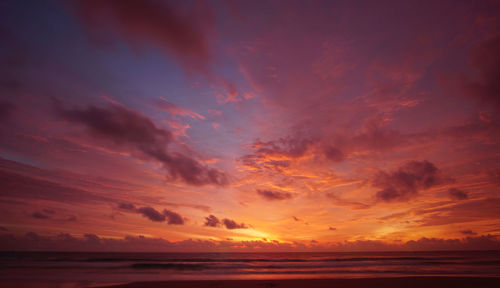 Scenic view of sea against dramatic sky during sunset