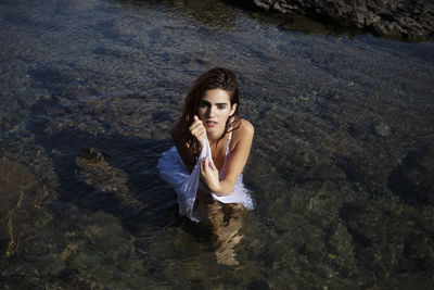 Portrait of a woman in a white dress sitting in the sea