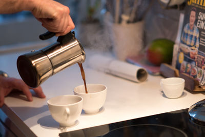 Close-up of hand pouring coffee in cafe