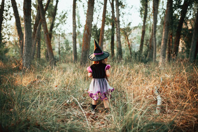 Rear view of woman standing on field in forest