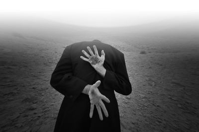 Man with dirty hands standing on landscape against sky