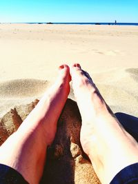 Low section of person relaxing on sand at beach