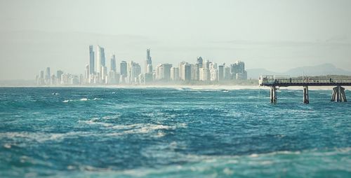 Scenic view of sea and cityscape against clear sky