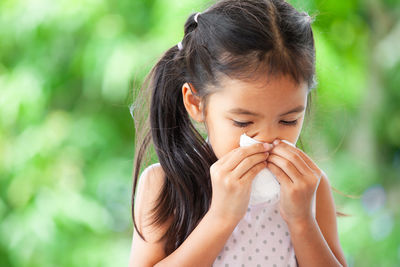 Girl wiping nose with tissue paper