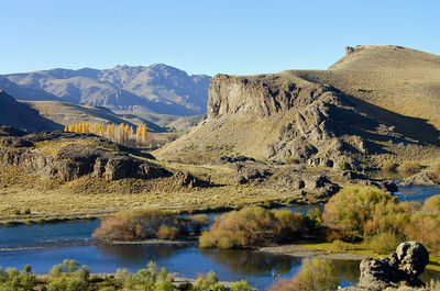 Scenic view of lake and mountains against clear blue sky